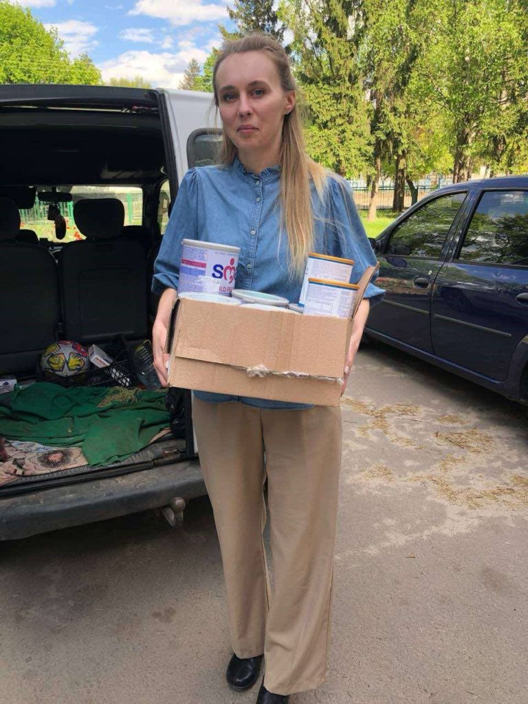 One of ladies from the team unloading baby food from a car