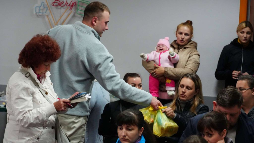 One of the team handing out bags of aid to people sat at the Centre