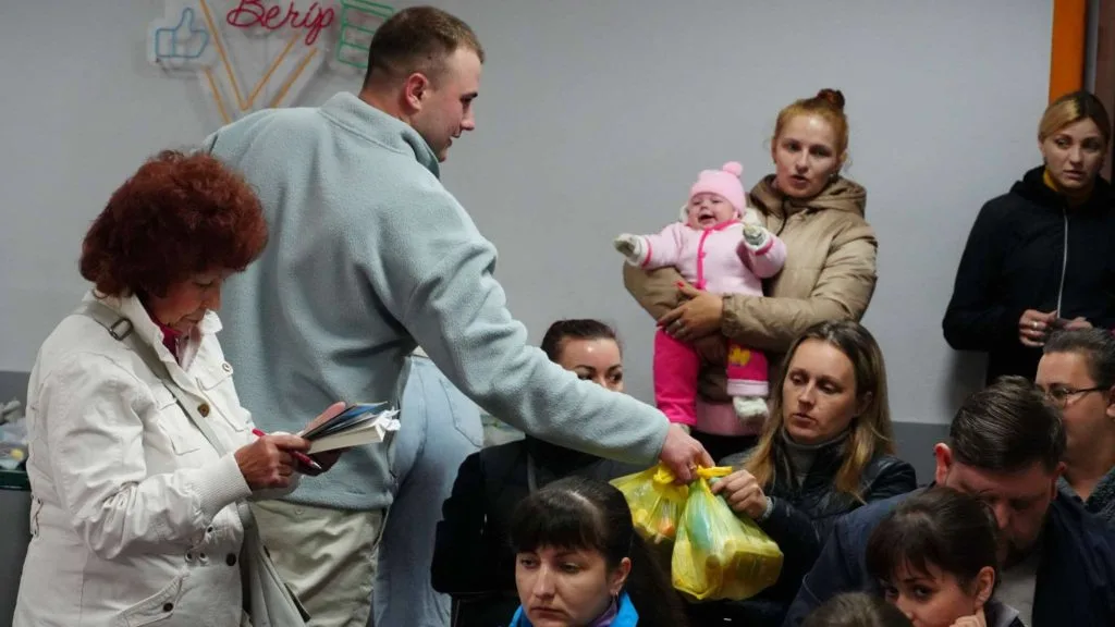 One of the team handing out bags of aid to people sat at the Centre
