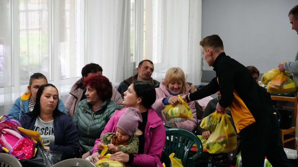 Two of the team handing out bags to aid to people sat in the Centre