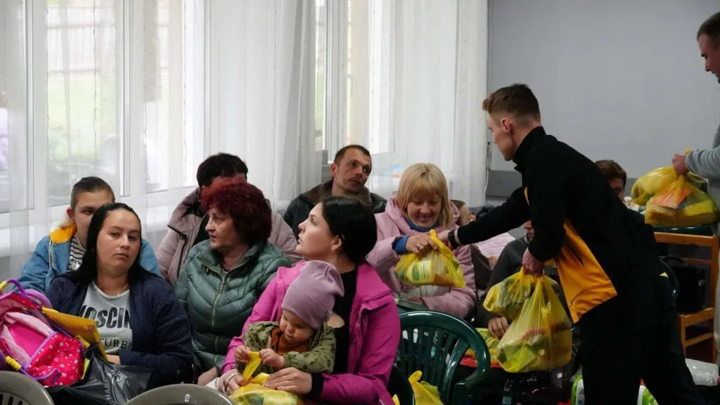 Two of the team handing out bags to aid to people sat in the Centre