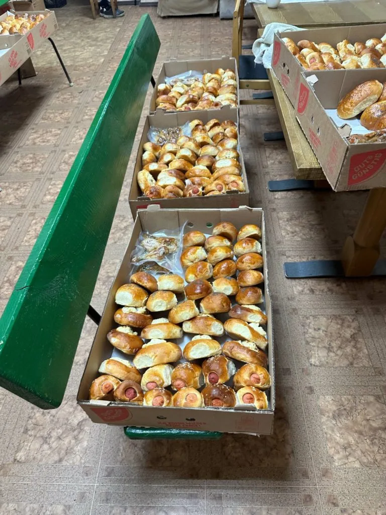 Cardboard trays full of lots of baked goods laid out on benches in a room