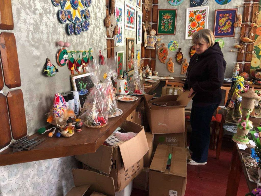 Boxes of candles on the floor of a craft shop with lots of colourful items displayed on the walls