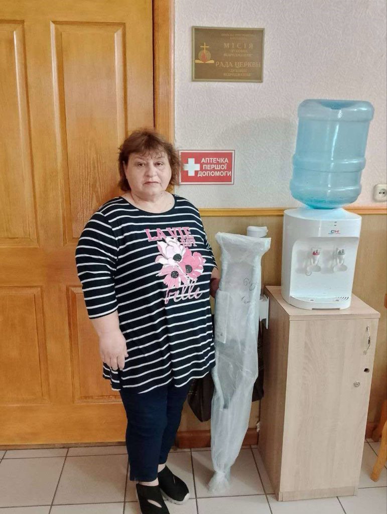 A lady standing next to a bag containing donated crutches