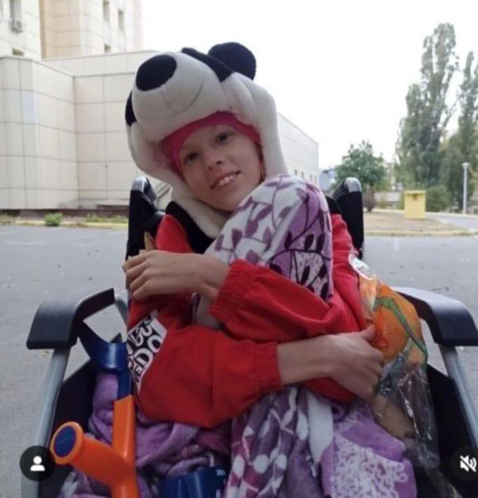 Sophia sat in her wheelchair wrapped up in a warm hat and blanket outside