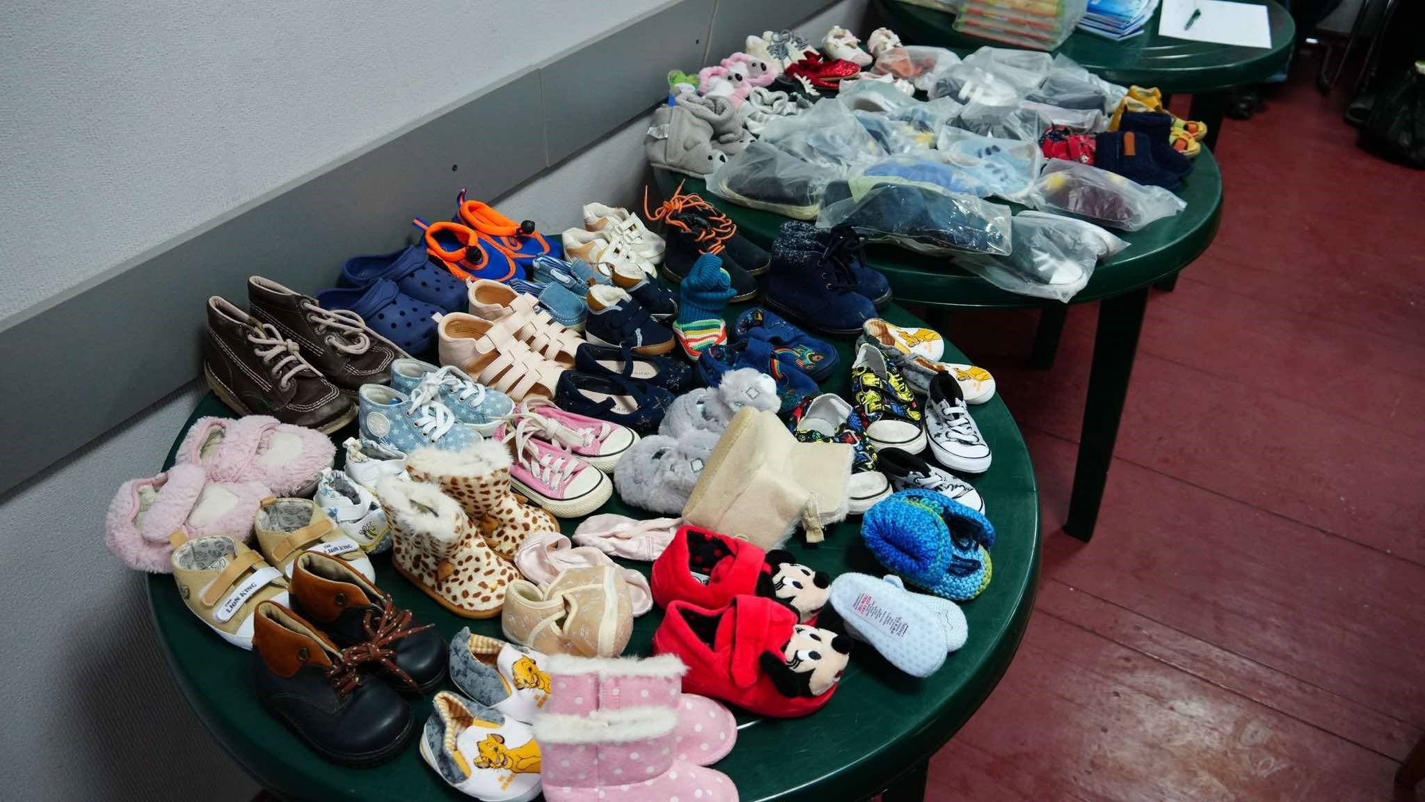 Two large round plastic garden tables full of donated shoes for children of all types