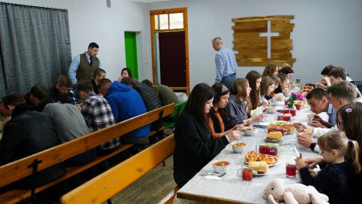 Some of the youth sat on benches around long tables eating a meal