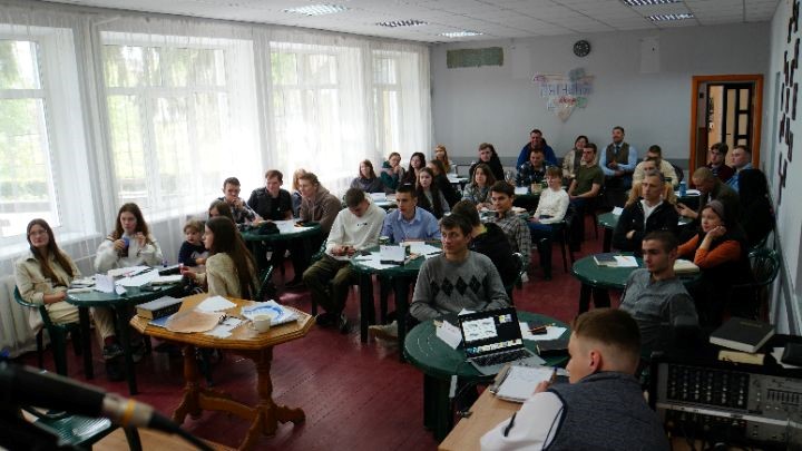 Youth sat around tables in a seminar as seen from the front of the venue