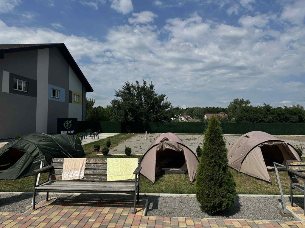 Camping tents set up beside the Centre under a partly cloudy sky.