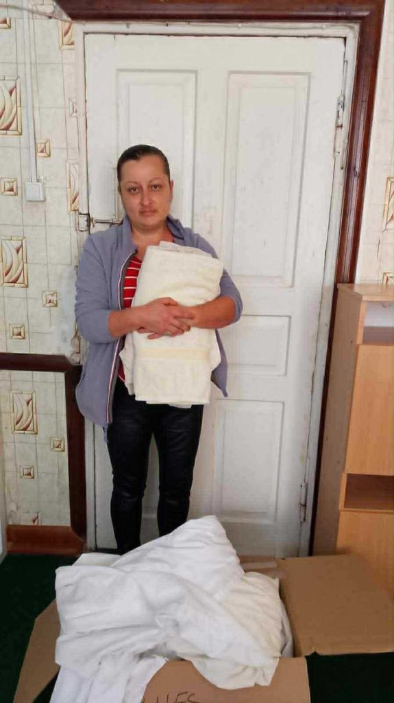 Woman holding fresh donated bedding standing in front of a door