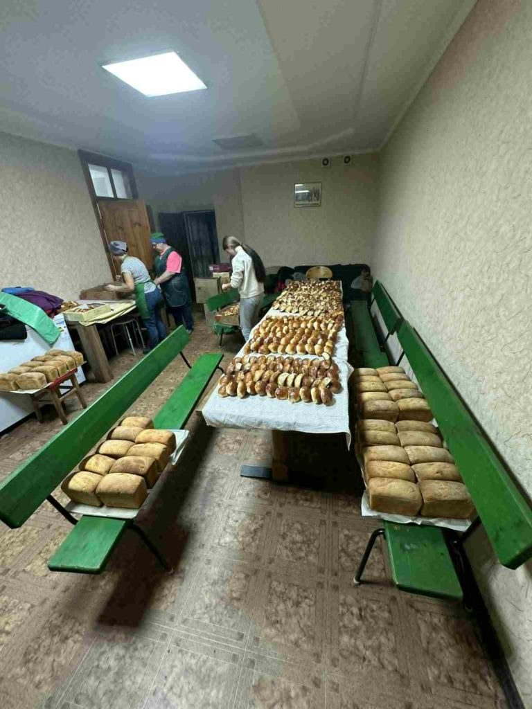Tables filled with rows of freshly baked loaves of bread being prepared for distribution.