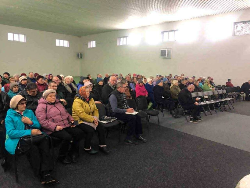 A large group of elderly and refugees seated inside the hall at the Centre during a service.