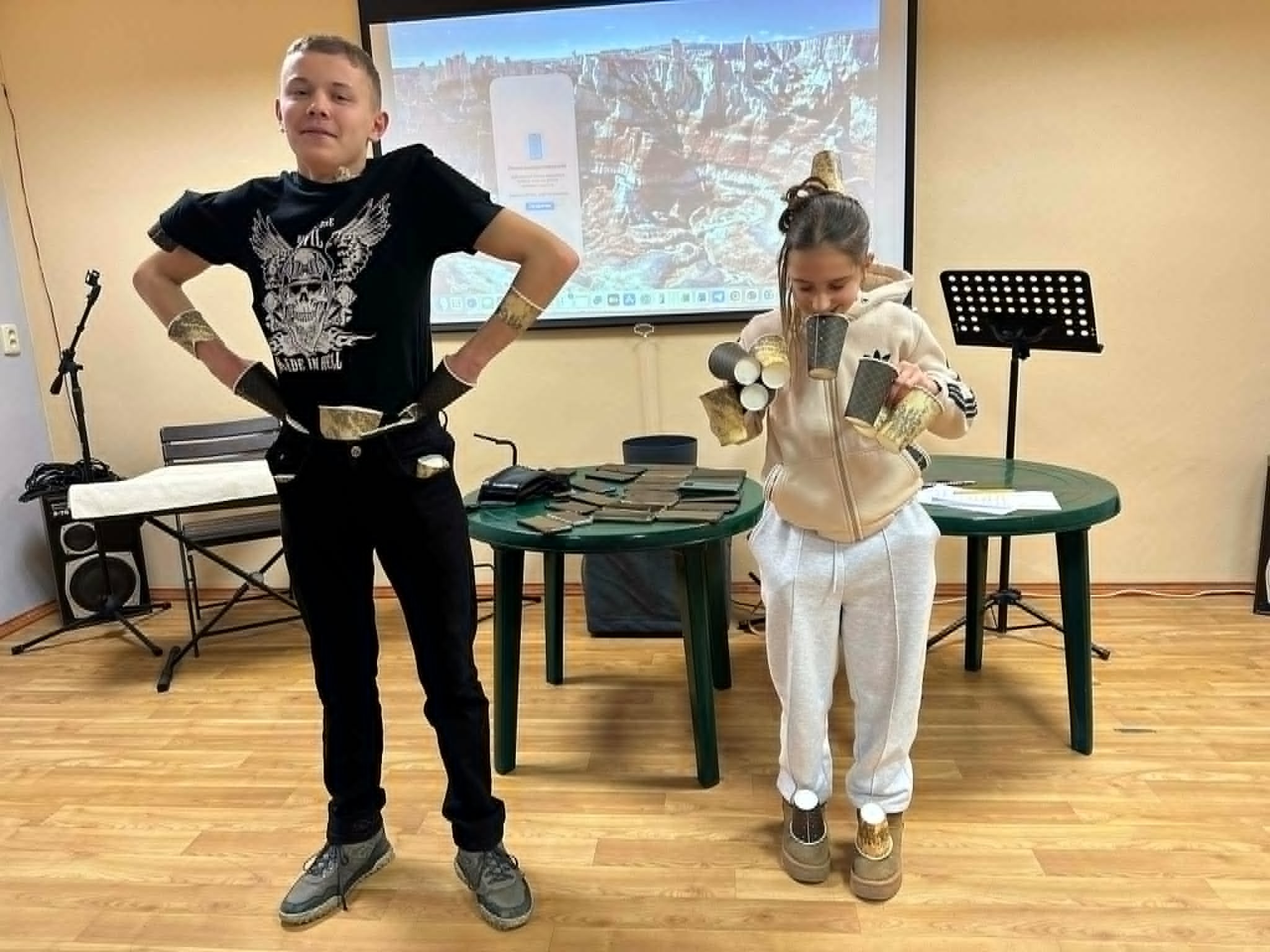 Boy and girl at a youth meeting wearing paper cup props on their arms and legs during a game.