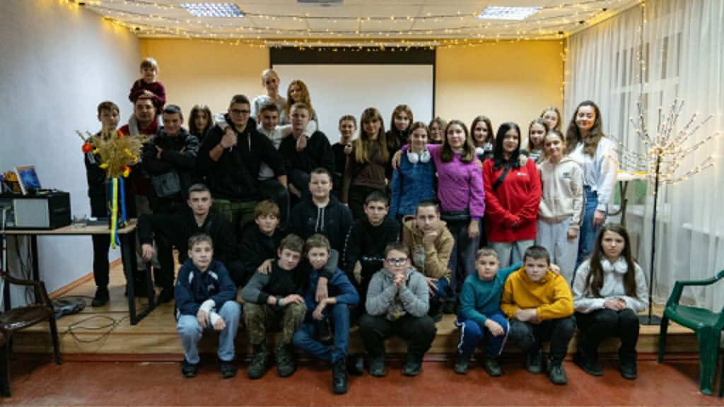 Large group of children and teenagers posing for a group photo in the Centre with lights and decorations.