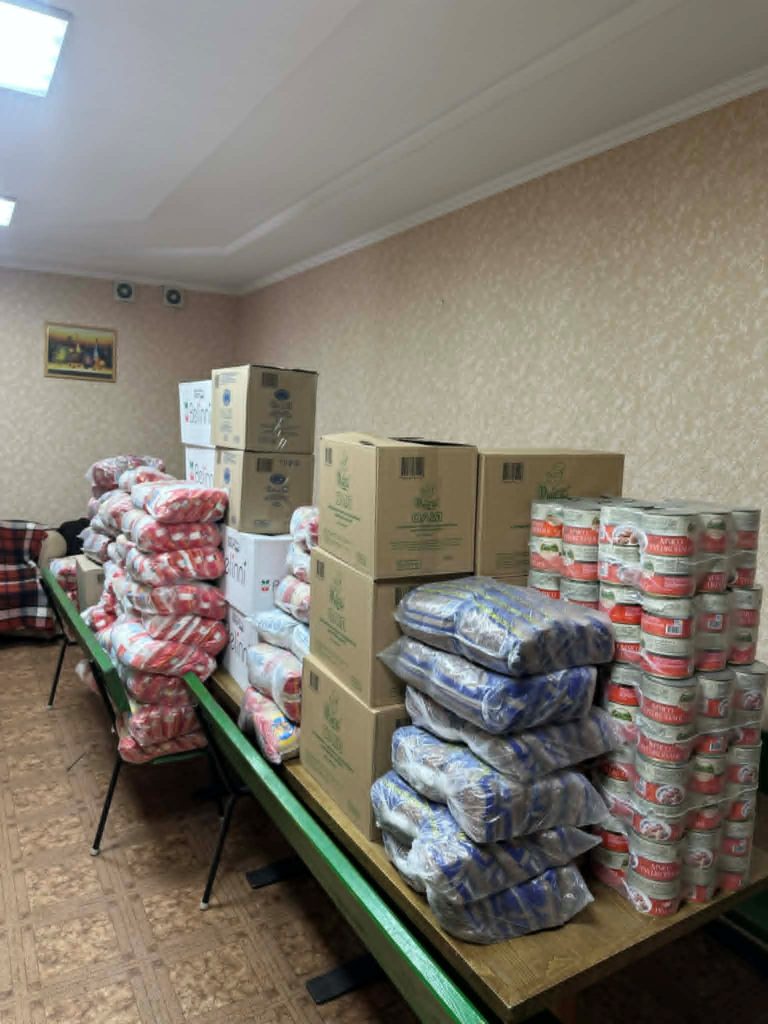 Tables stacked with boxes, canned food, and packaged supplies for aid distribution.