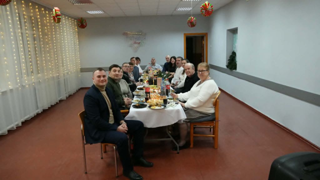 The Lebedyn team seated at a long table sharing a Christmas Eve meal together indoors.