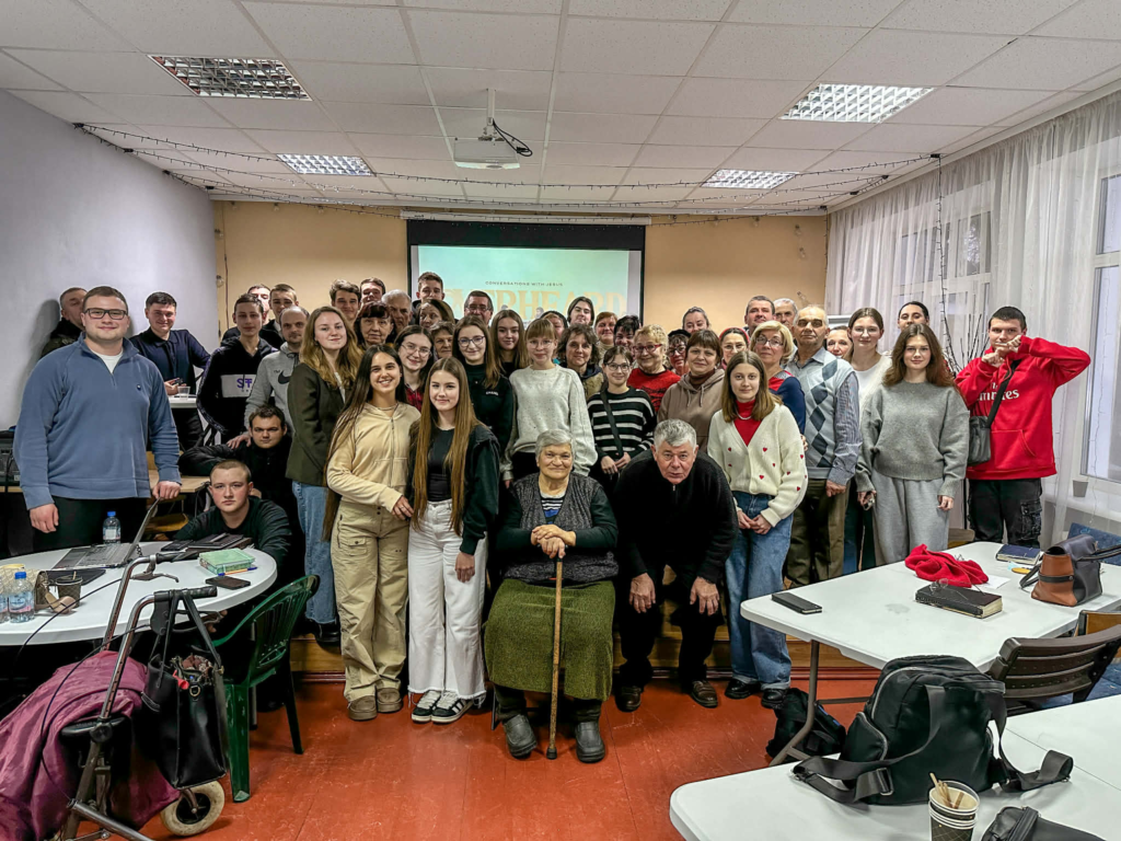 Participants and volunteers stand together after a conference, showing unity and shared commitment to serving their community.
