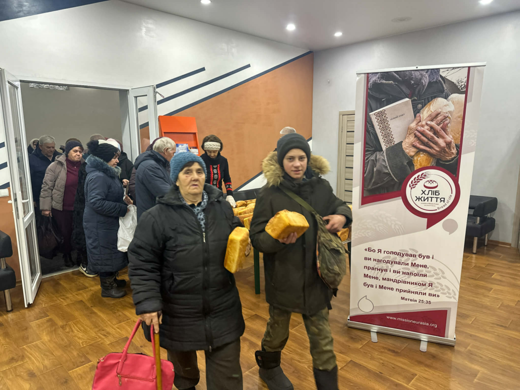 People walk through the Centre carrying loaves of bread after receiving food assistance from the bakery.
