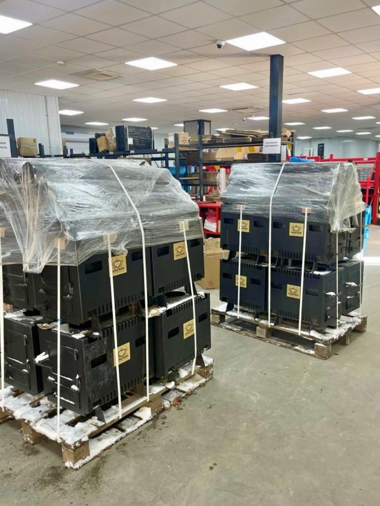 Wood-burning stoves sat on snow covered pallets in a warehouse prepared for delivery to families without reliable heating in vulnerable communities.