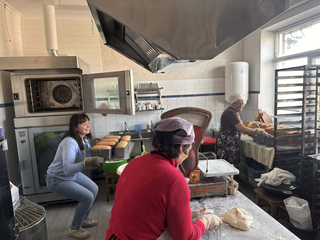 Volunteers in the bakery prepare and bake loaves of bread, working together to provide food for the community.