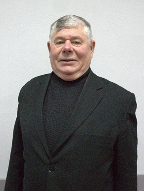 Portrait photo of Pastor Sergey standing indoors, wearing a dark jacket and looking at the camera.