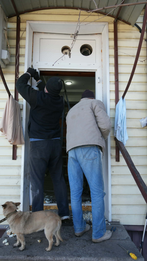 Volunteers remove a door frame to widen the entrance so a large oven can be brought into the Centre.