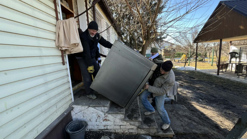 Volunteers carefully carry a heavy industrial oven up steps into the Centre for installation.