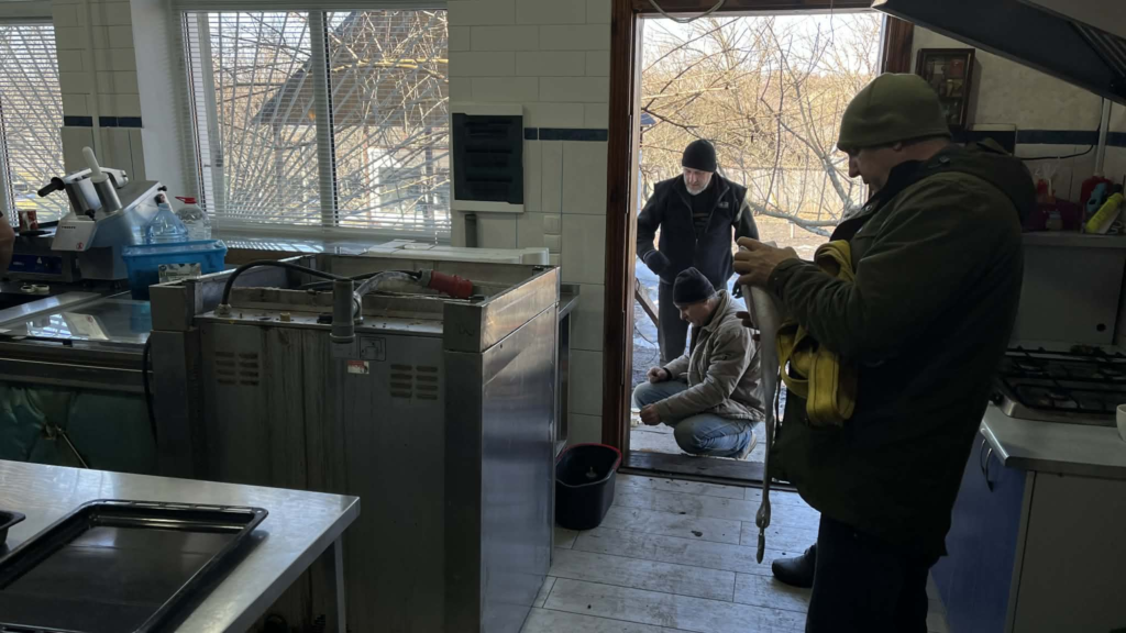 Volunteers install a new industrial oven in a kitchen in the bakery at the Centre.