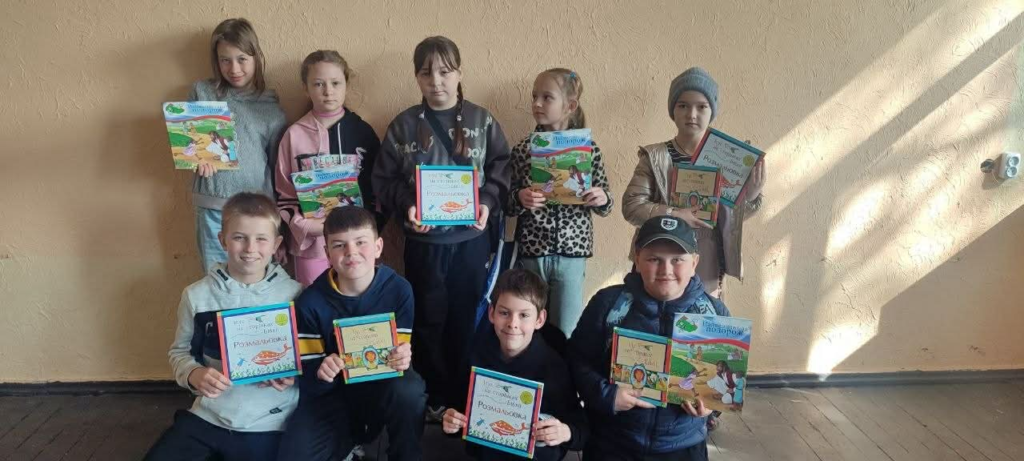 A group of children stand together holding copies of The Jesus Storybook Bible, smiling after receiving them during the Easter camp.