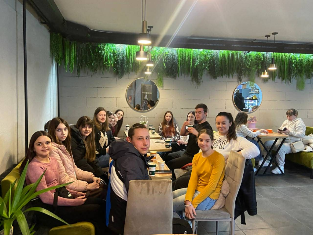 A group of teenagers sit together around tables, sharing drinks and spending time in fellowship.