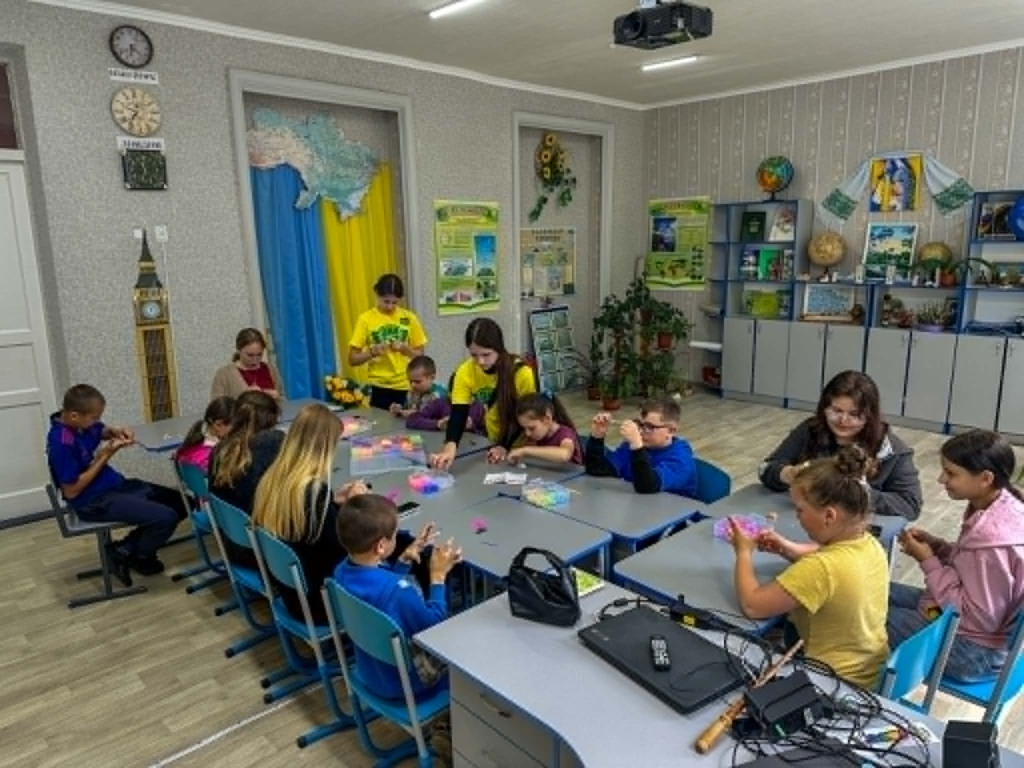 Children work on creative crafts with the help of volunteers during a summer camp programme.