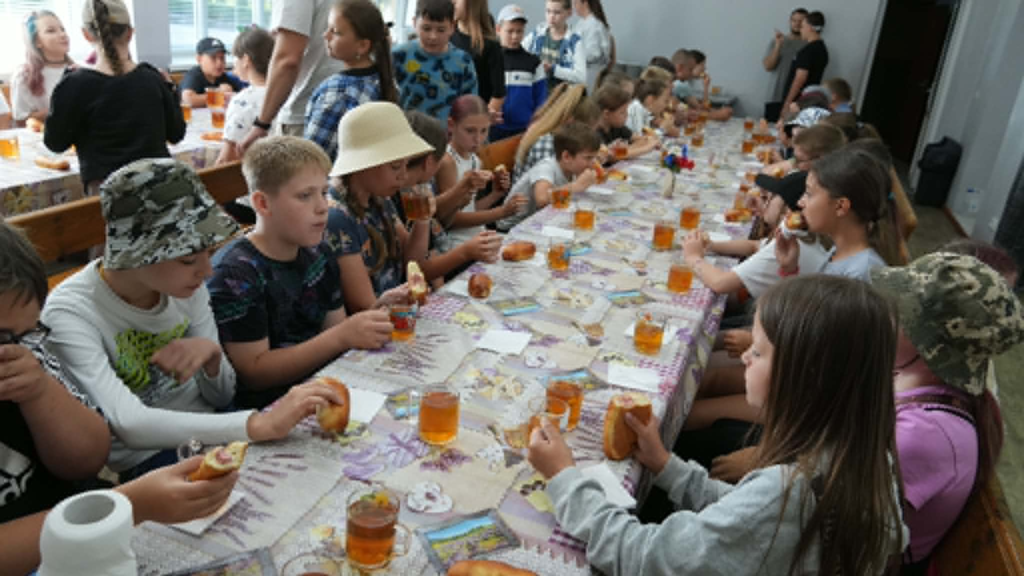 Children share lunch together during a break at a summer camp at the Centre.