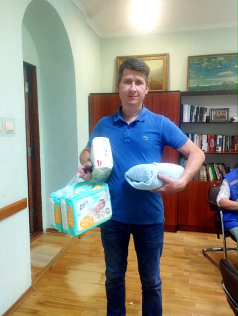 Man holding donated nappies, bedding and essential supplies.