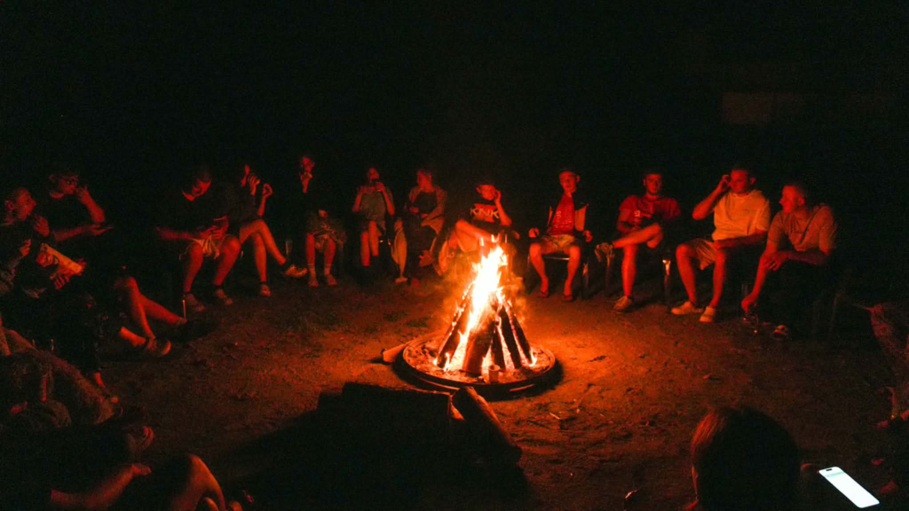 Teenagers gathered around a campfire during the 2026 summer teen camp in Lebedyn.