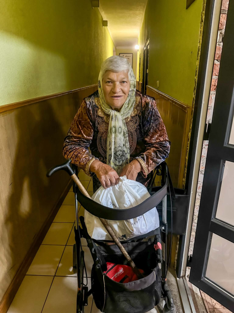 Elderly woman with a walking aid receiving an emergency food bag.